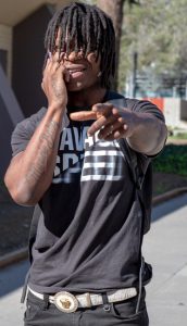 A student walking while talking on the phone and pointing.